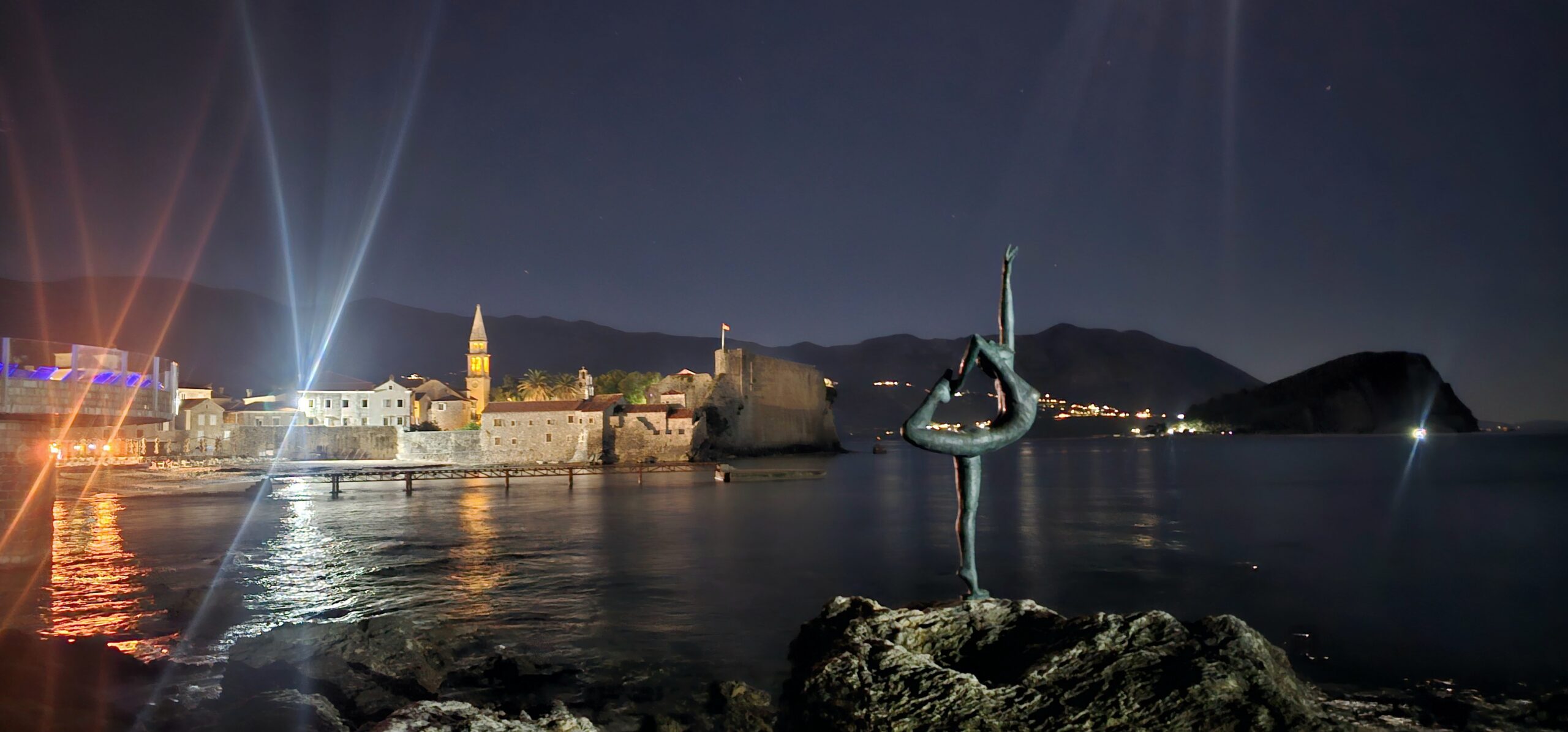 Budva’s illuminated old town and waterfront at night.